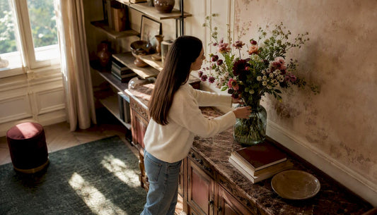 Eine Frau arrangiert eine Vase als stilvollen Akzent auf einem modernen Sideboard.
